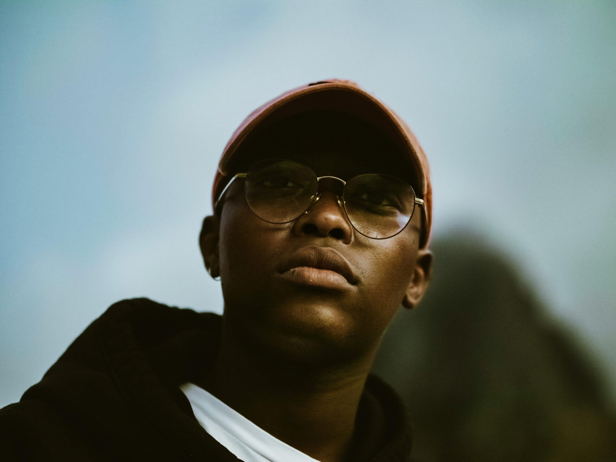A dramatic portrait of a man in Cape Town wearing eyeglasses and a cap.